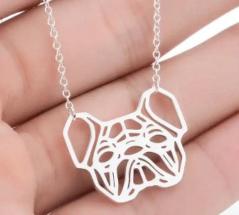 A silver necklace with a cutout pendant shaped like a French bulldog, held in a person's hand.