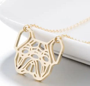 A gold pendant necklace featuring a stylized dog head cutout design, suspended from a delicate gold chain against a clean white background