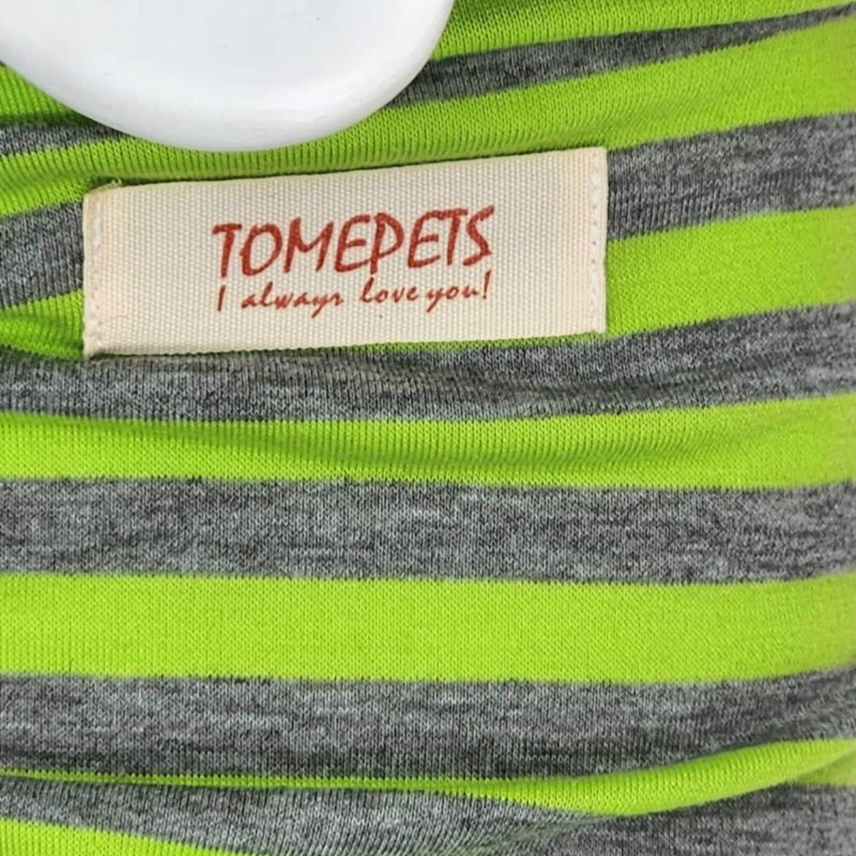 Close-up of a striped knit garment with bright neon green and heather gray horizontal stripes, featuring a cream fabric label that reads 'TOMEPETS I always love you!' in red text.